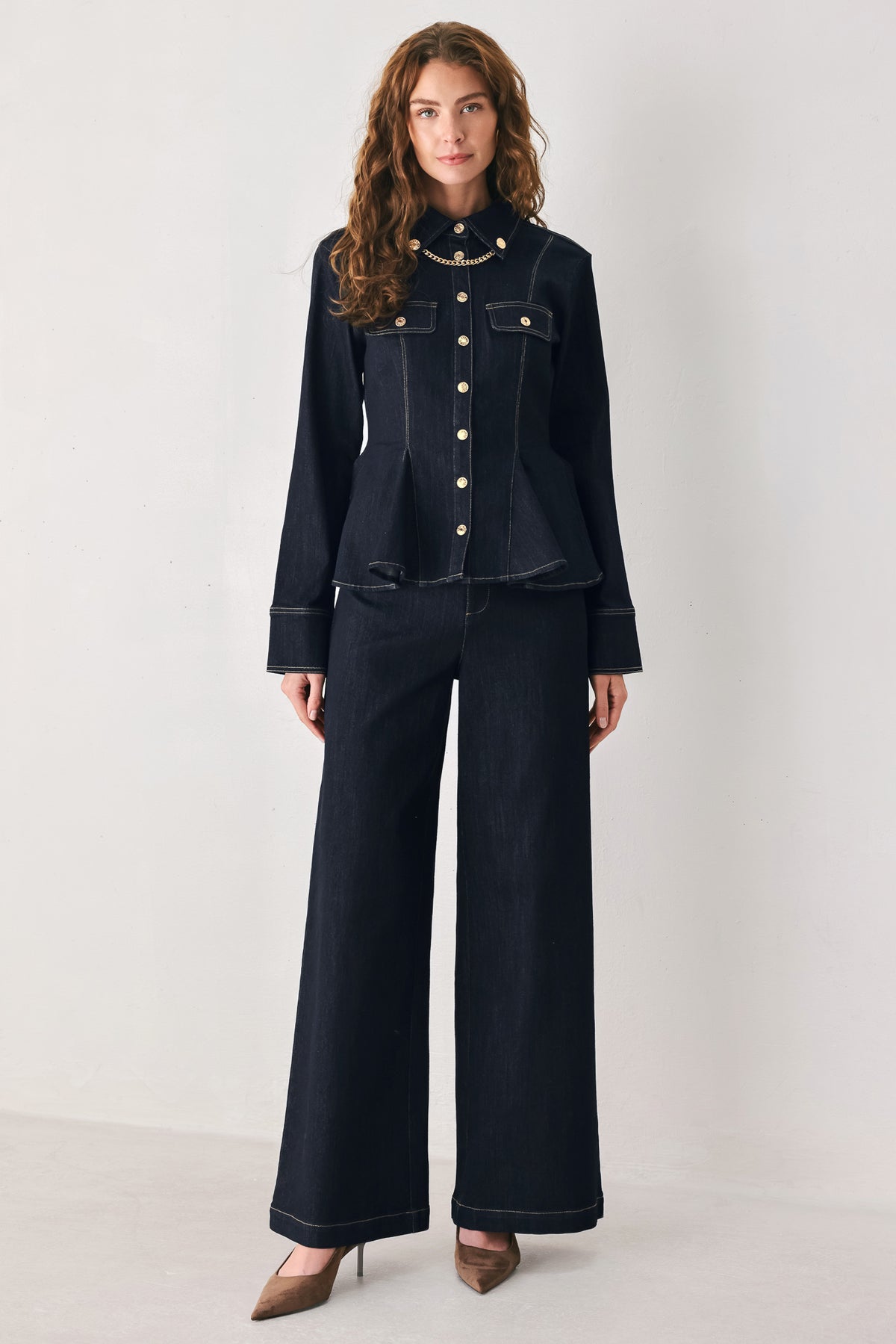 Woman wearing a navy blue denim long sleep button up top with a peplum waist, a collar and chain connected to the corners of the collar | FREEMARKET
