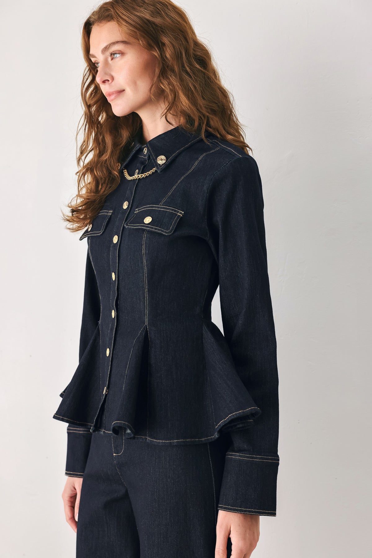 Woman wearing a navy blue denim long sleep button up top with a peplum waist, a collar and chain connected to the corners of the collar | FREEMARKET