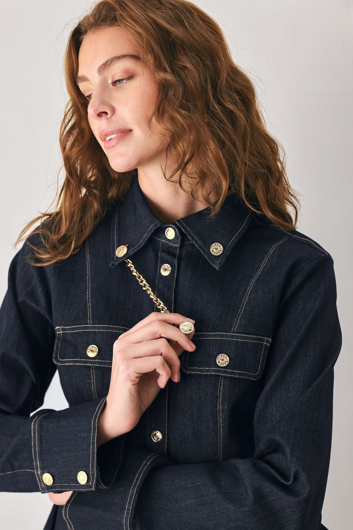 Woman wearing a navy blue denim long sleep button up top with a peplum waist, a collar and chain connected to the corners of the collar | FREEMARKET