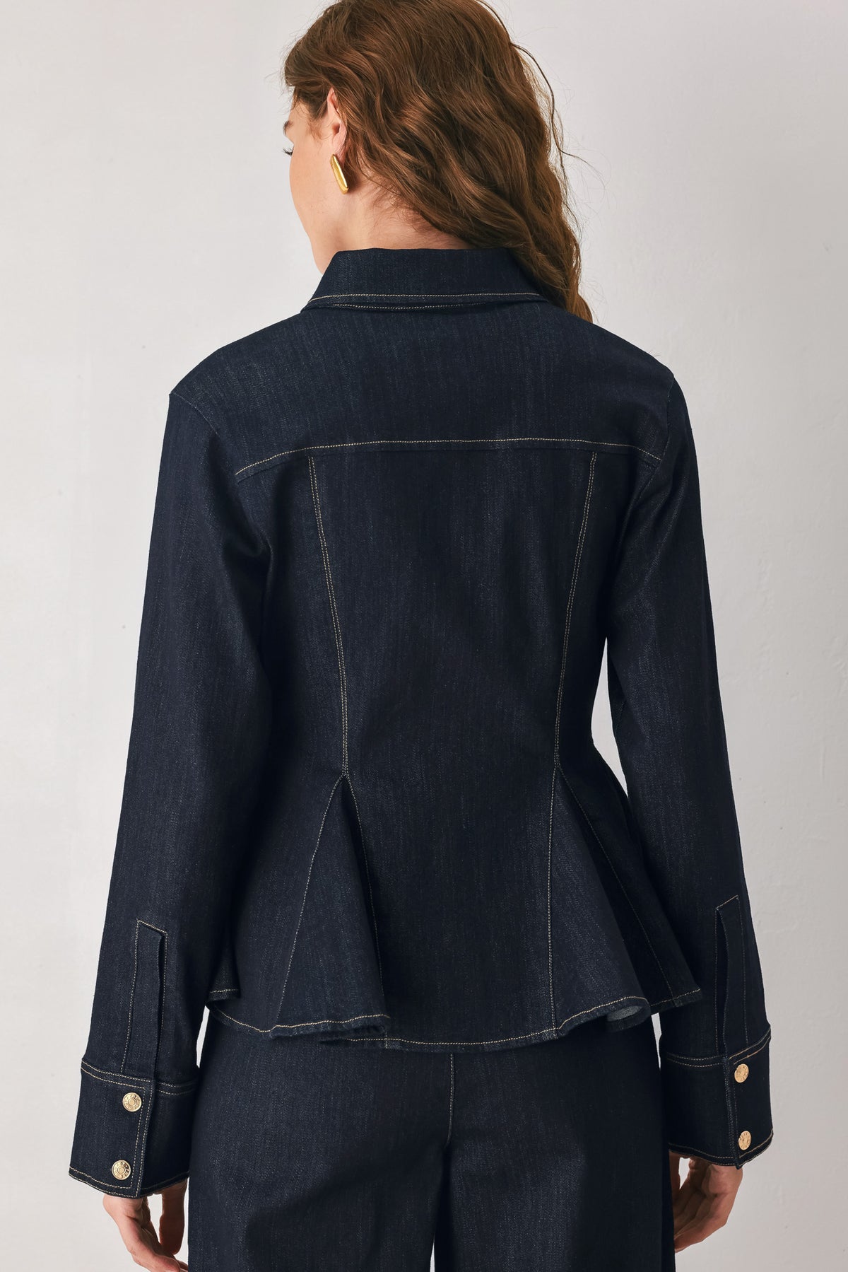 Woman wearing a navy blue denim long sleep button up top with a peplum waist, a collar and chain connected to the corners of the collar | FREEMARKET