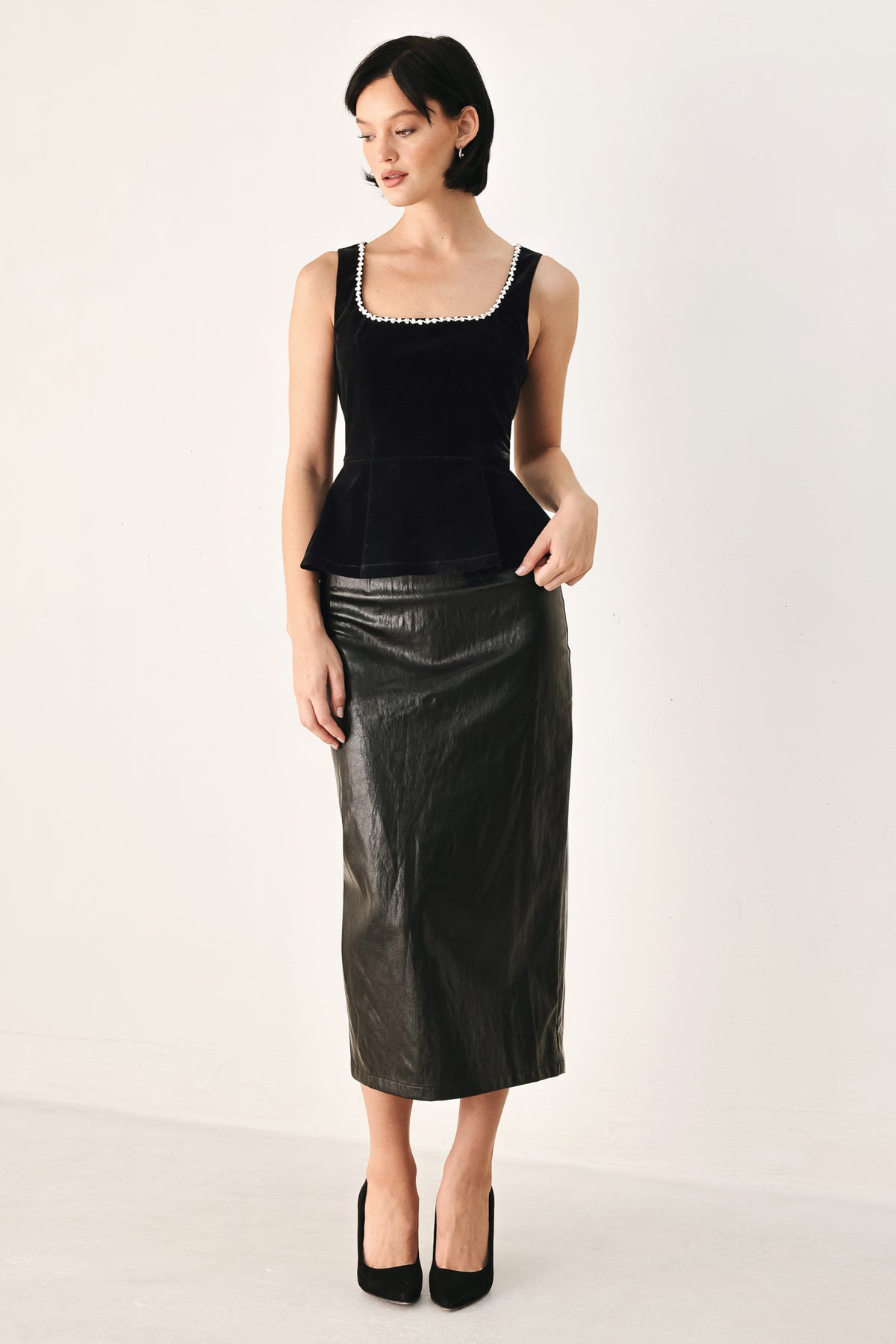 A woman modeling a black velvet sleeveless top with a pearl-trimmed square neckline and a peplum waist | FREEMARKET
