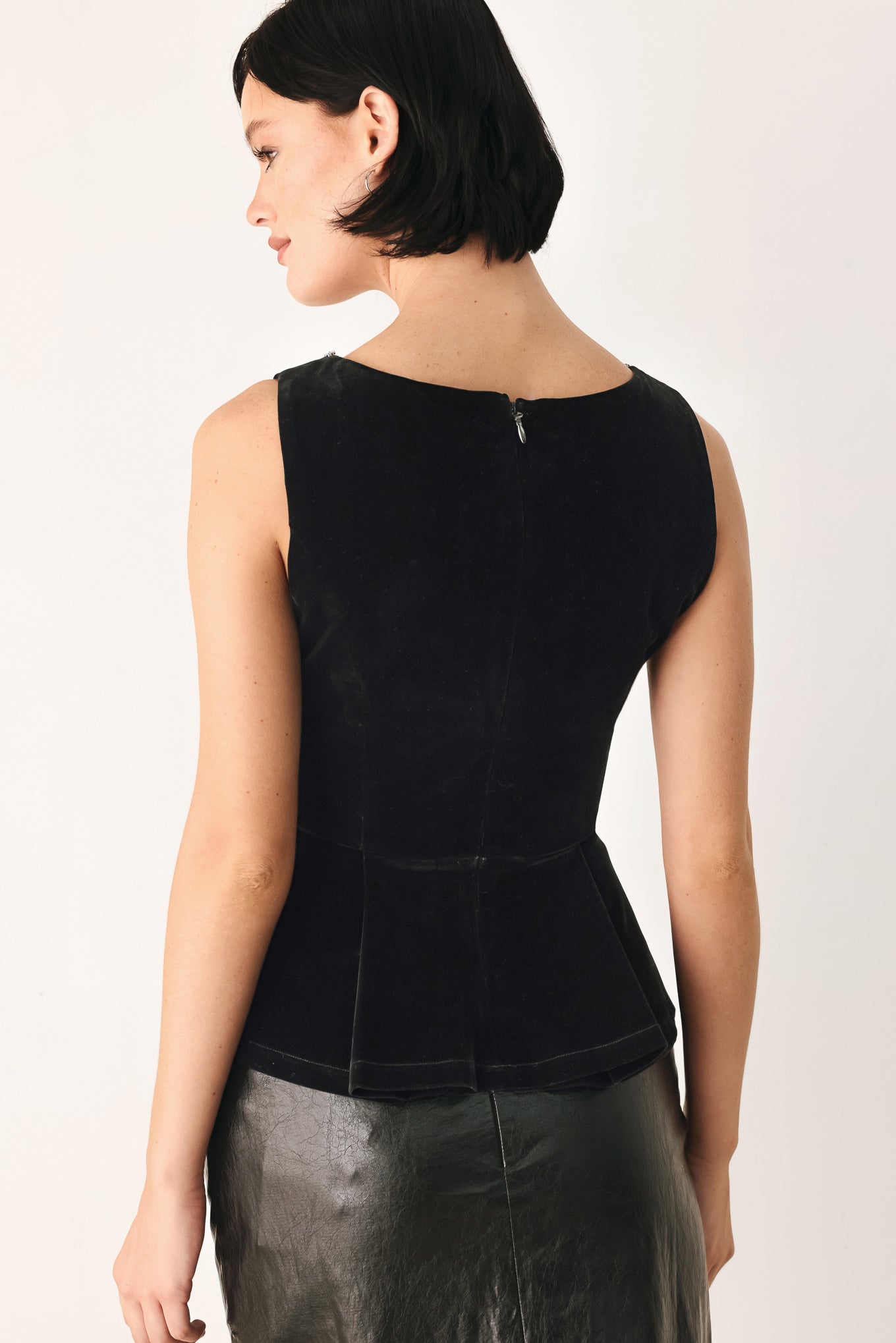 A woman modeling a black velvet sleeveless top with a pearl-trimmed square neckline and a peplum waist | FREEMARKET