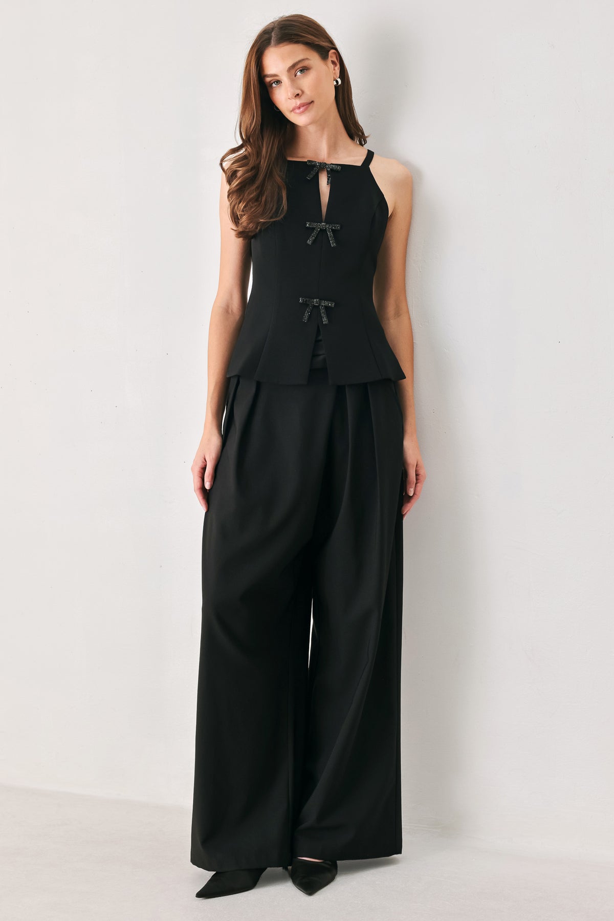 A woman wearing a black sleeveless top with bow details | FREEMARKET