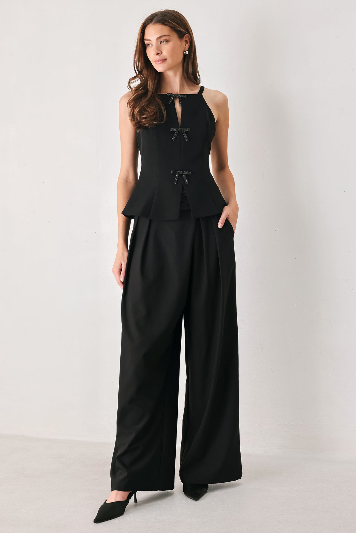 A woman wearing a black sleeveless top with bow details | FREEMARKET