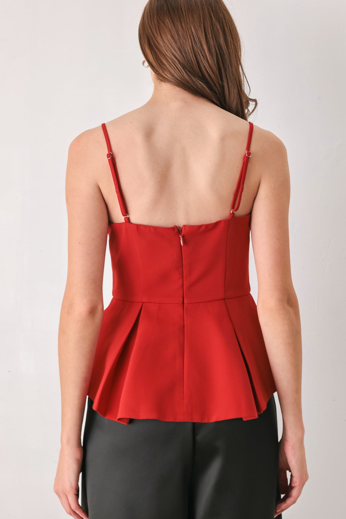 A woman modeling a red spaghetti-strap peplum top with a sweetheart neckline and keyhole cutout | FREEMARKET