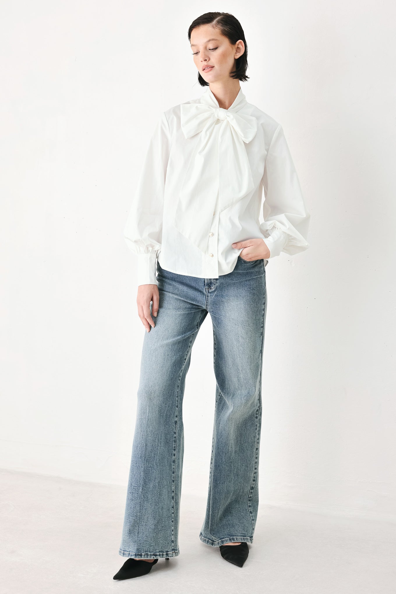 A woman wearing a white long-sleeve blouse with a large bow at the collar | FREEMARKET
