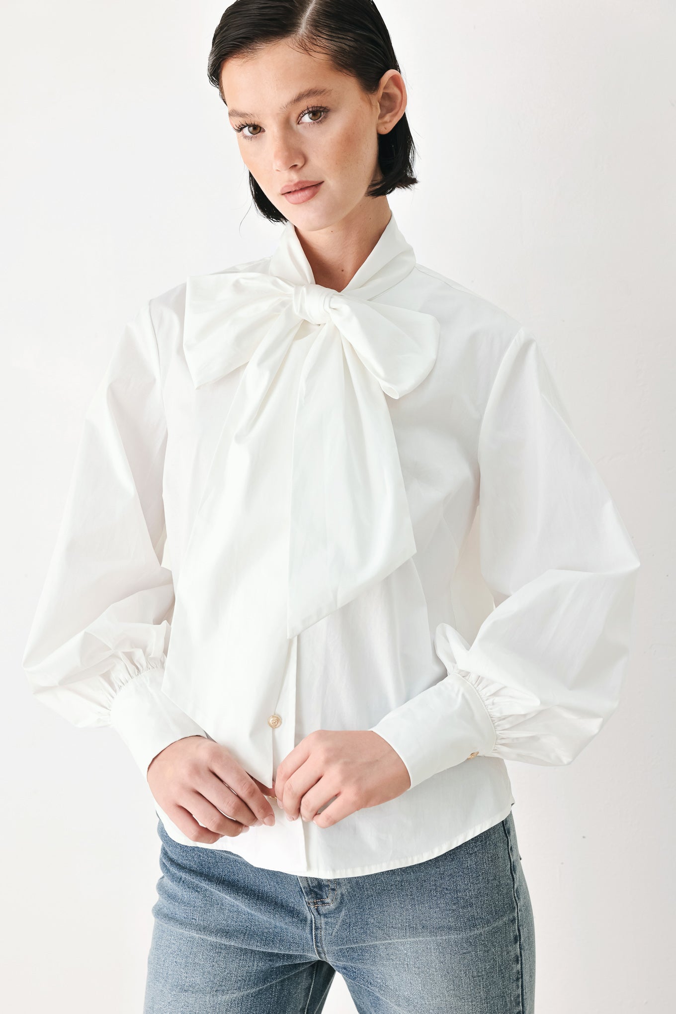 A woman wearing a white long-sleeve blouse with a large bow at the collar | FREEMARKET