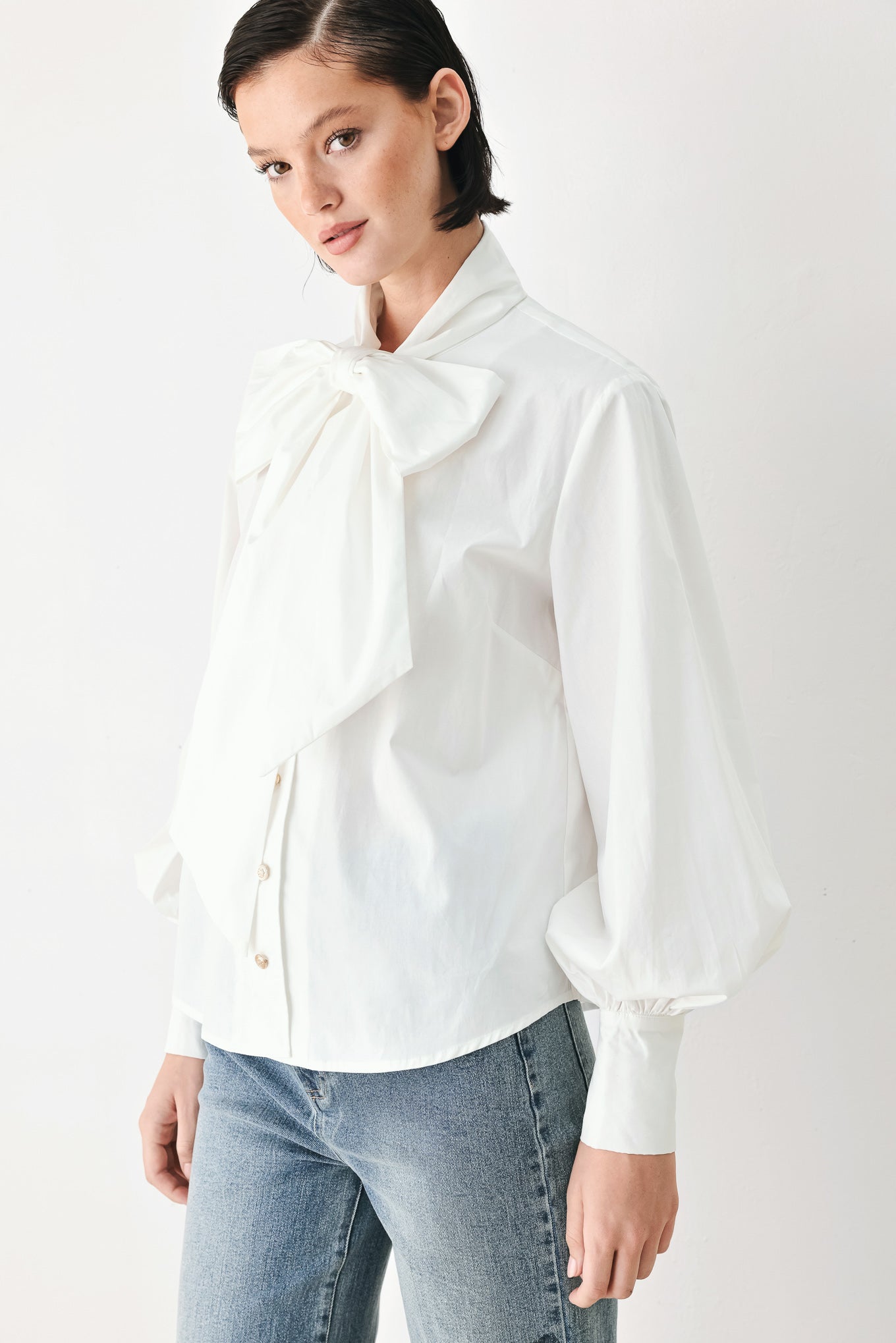 A woman wearing a white long-sleeve blouse with a large bow at the collar | FREEMARKET