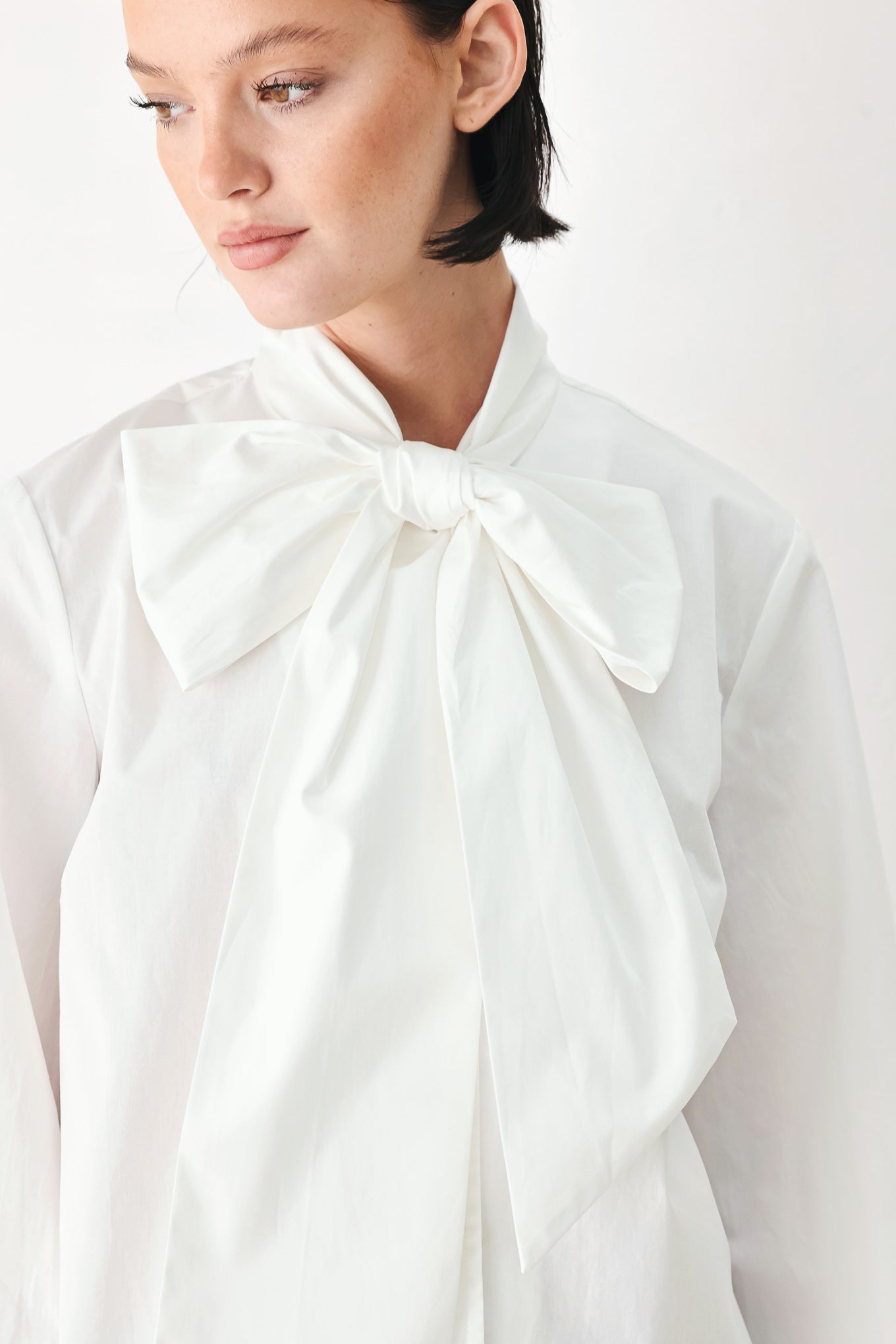 A woman wearing a white long-sleeve blouse with a large bow at the collar | FREEMARKET