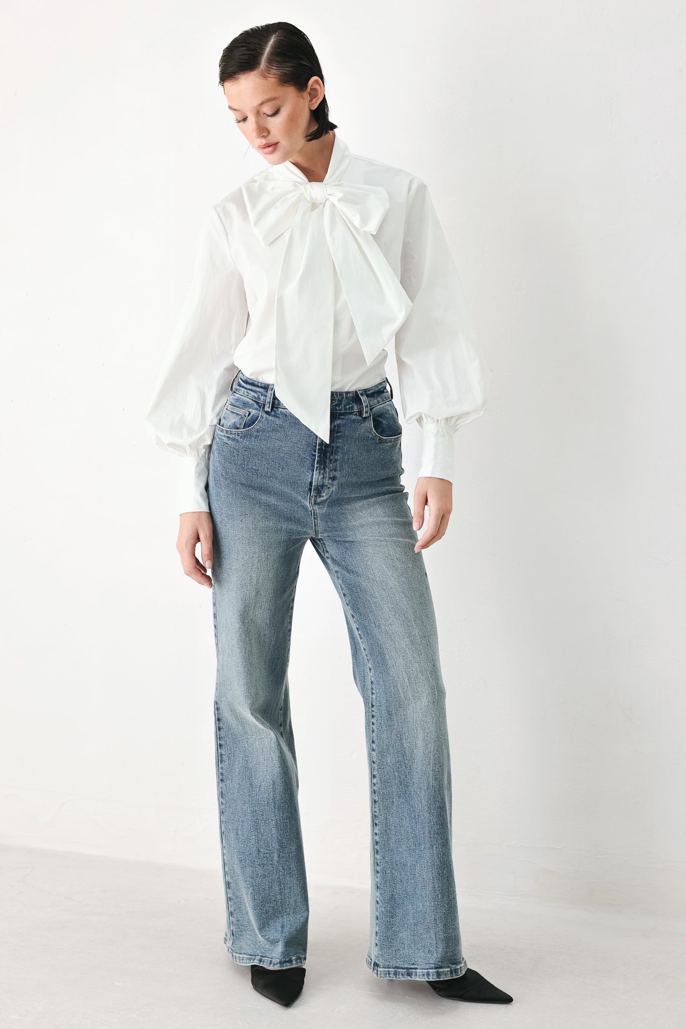 A woman wearing a white long-sleeve blouse with a large bow at the collar | FREEMARKET