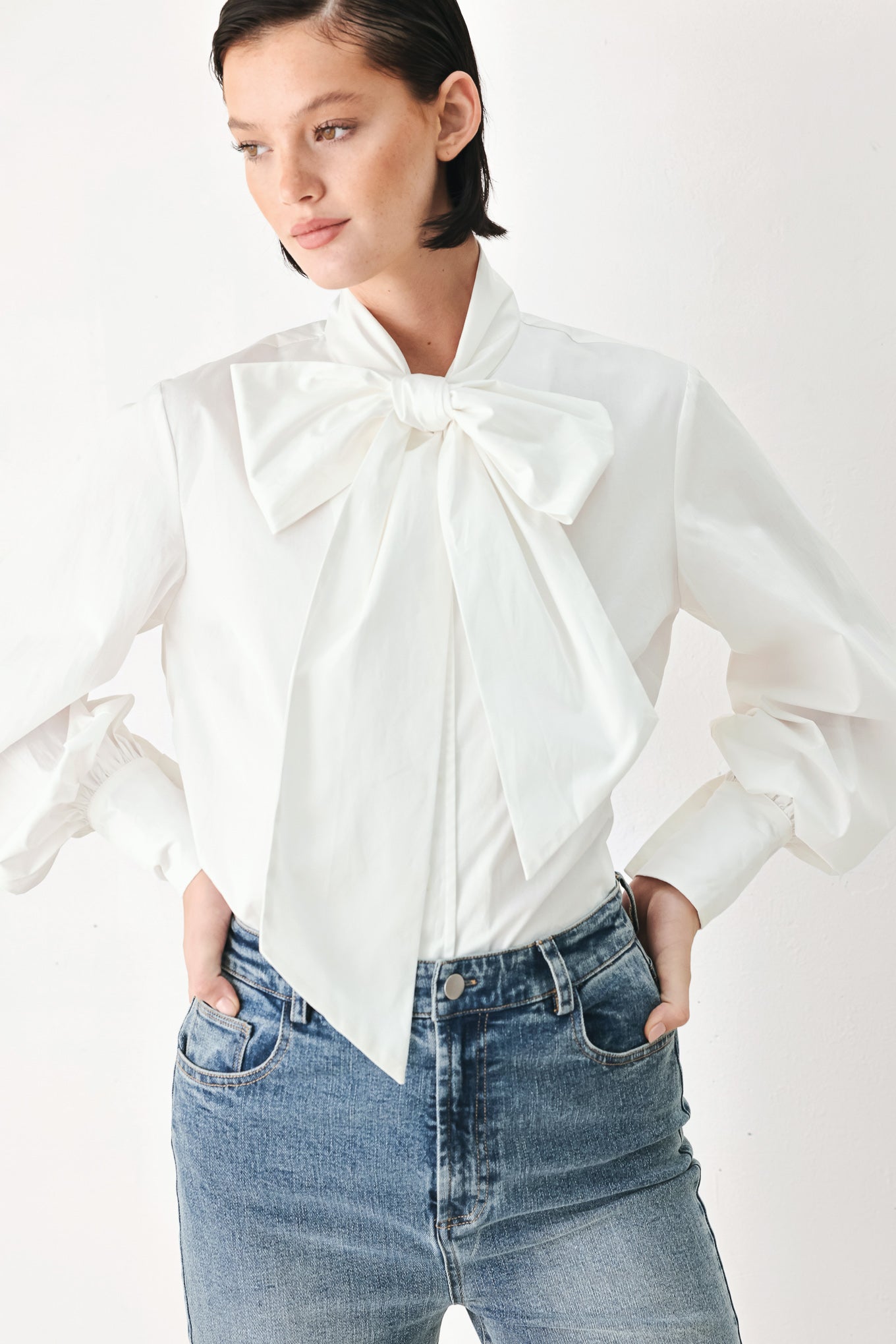 A woman wearing a white long-sleeve blouse with a large bow at the collar | FREEMARKET