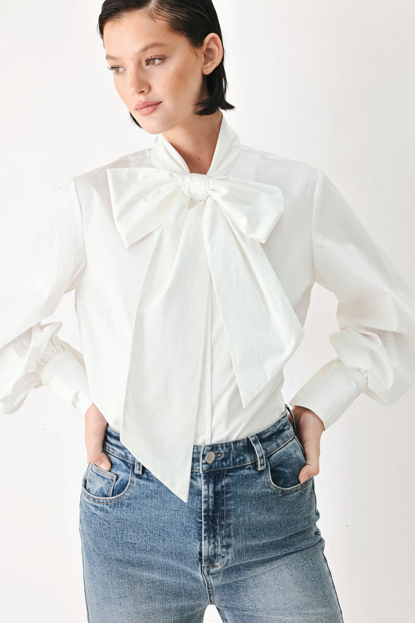 A woman wearing a white long-sleeve blouse with a large bow at the collar | FREEMARKET