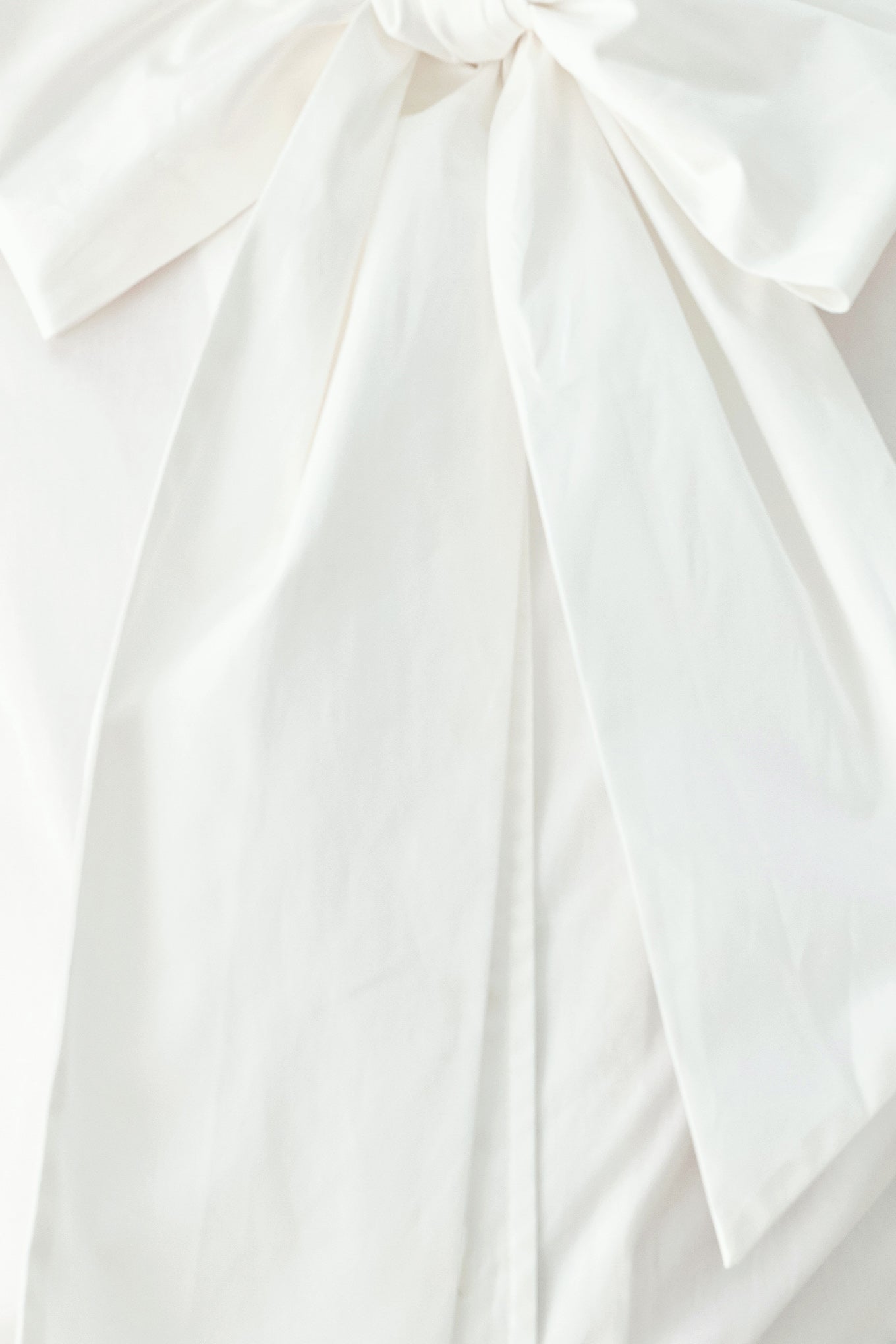 A woman wearing a white long-sleeve blouse with a large bow at the collar | FREEMARKET
