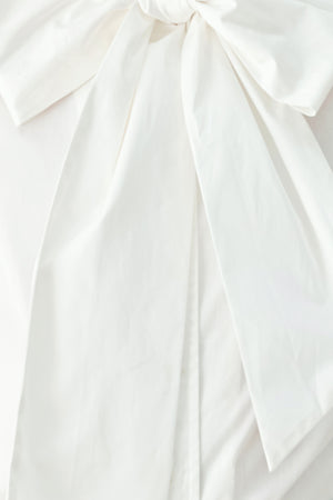 A woman wearing a white long-sleeve blouse with a large bow at the collar | FREEMARKET