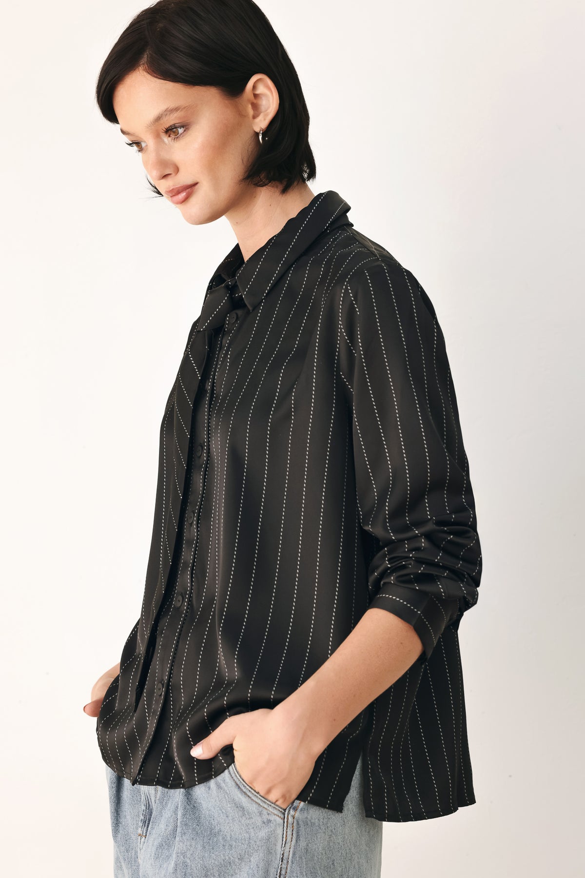 A woman wearing a black long-sleeve button-up shirt with thin white vertical pinstripes, styled with a matching striped tie | FREEMARKET