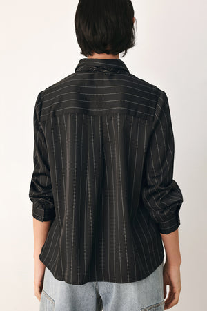 A woman wearing a black long-sleeve button-up shirt with thin white vertical pinstripes, styled with a matching striped tie | FREEMARKET