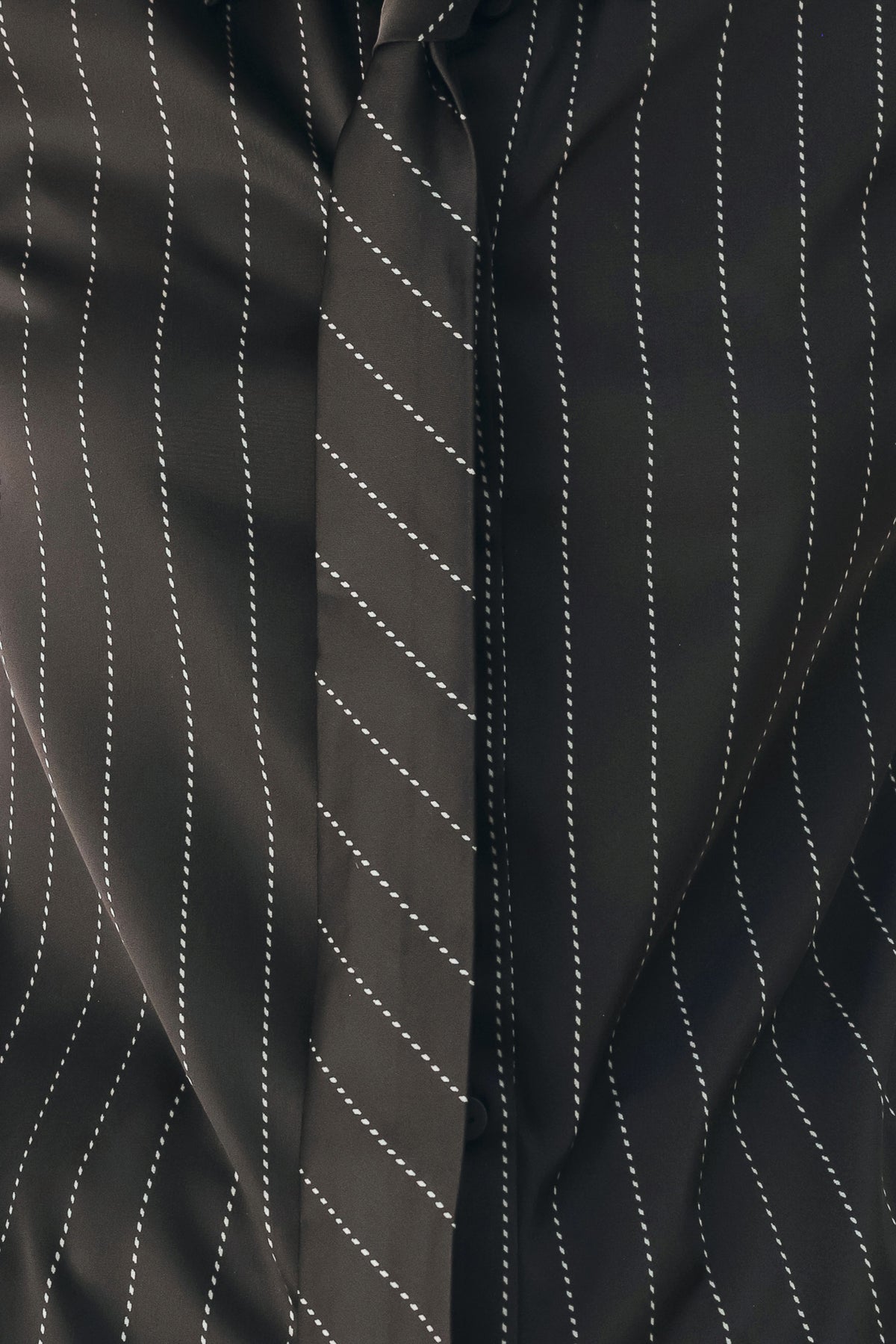 A woman wearing a black long-sleeve button-up shirt with thin white vertical pinstripes, styled with a matching striped tie | FREEMARKET