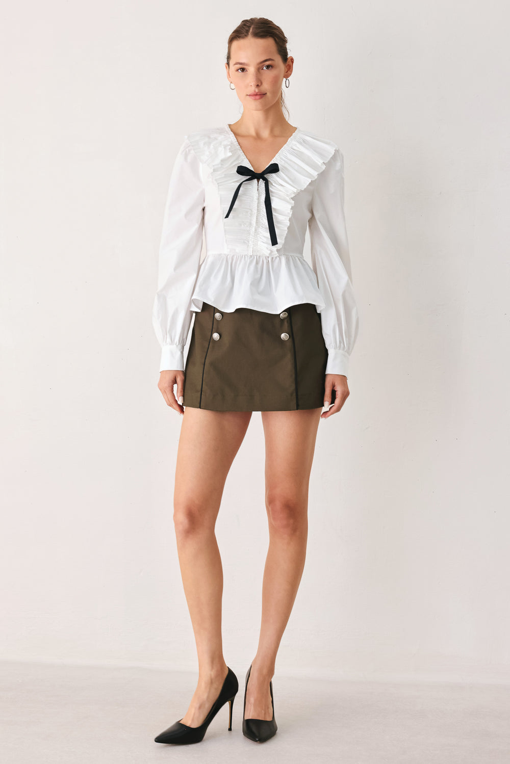 A woman wearing a white long-sleeve blouse with a ruffled V-neck, gathered waist, and a black ribbon bow at the center | FREEMARKET
