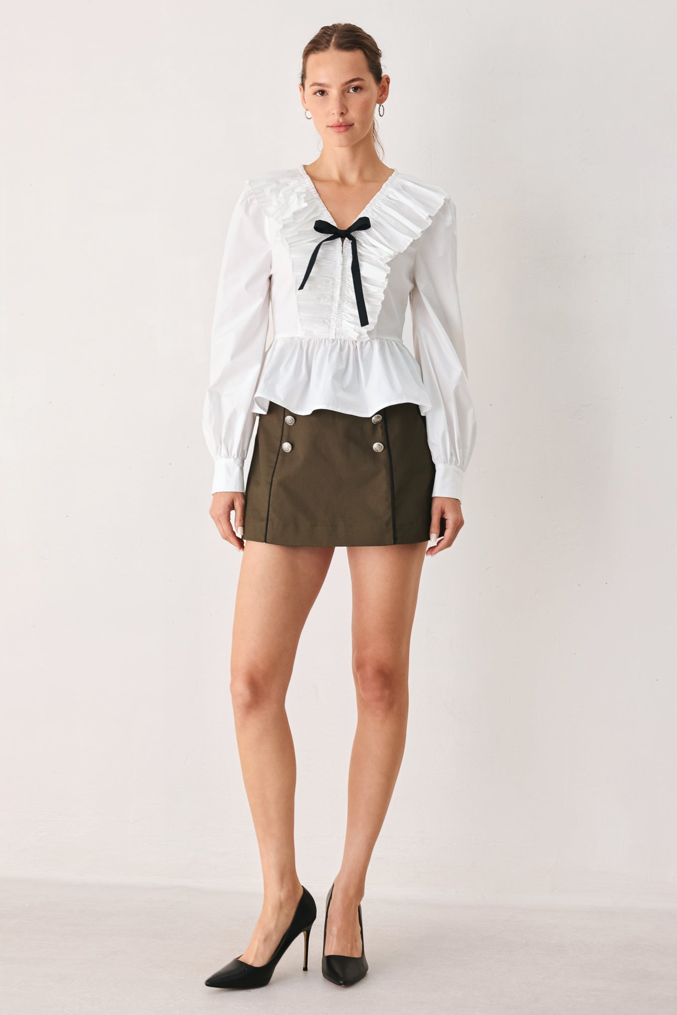 A woman wearing a white long-sleeve blouse with a ruffled V-neck, gathered waist, and a black ribbon bow at the center | FREEMARKET