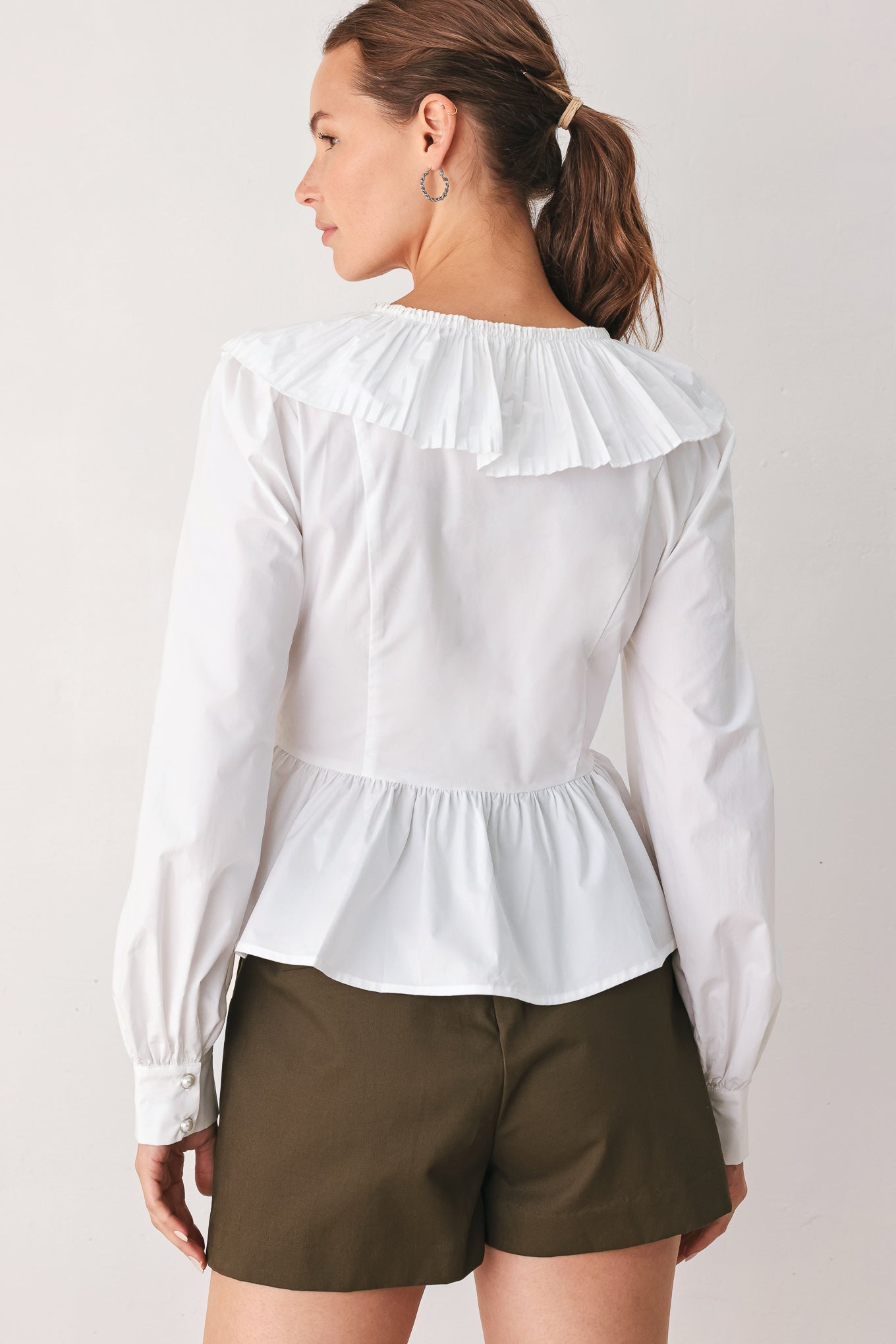 A woman wearing a white long-sleeve blouse with a ruffled V-neck, gathered waist, and a black ribbon bow at the center | FREEMARKET