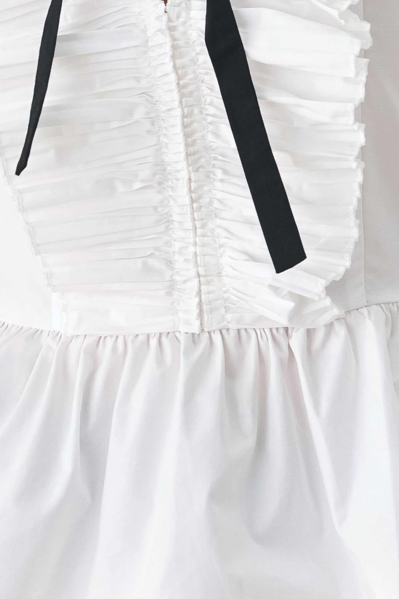 A woman wearing a white long-sleeve blouse with a ruffled V-neck, gathered waist, and a black ribbon bow at the center | FREEMARKET