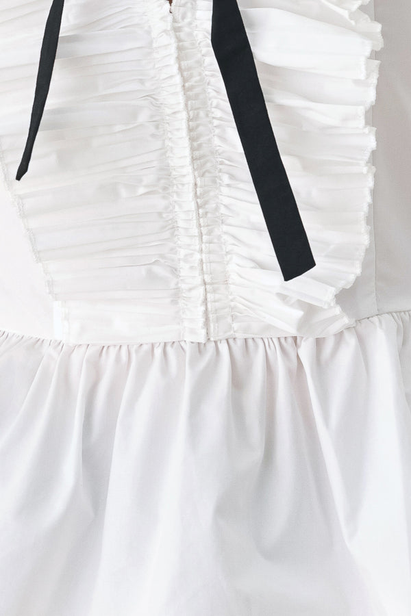 A woman wearing a white long-sleeve blouse with a ruffled V-neck, gathered waist, and a black ribbon bow at the center | FREEMARKET