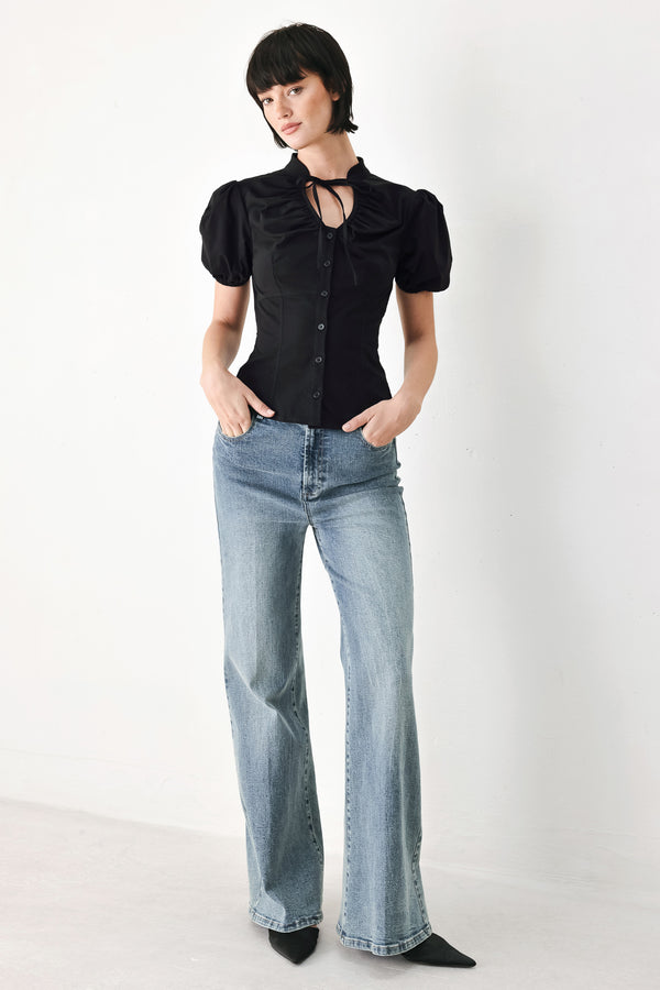 A woman wearing a black short-sleeve blouse with puff sleeves, a ruffled collar, and a keyhole cutout at the neckline | FREEMARKET