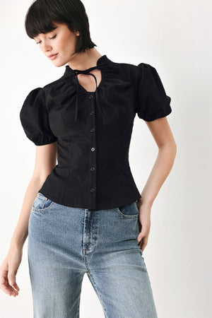 A woman wearing a black short-sleeve blouse with puff sleeves, a ruffled collar, and a keyhole cutout at the neckline | FREEMARKET