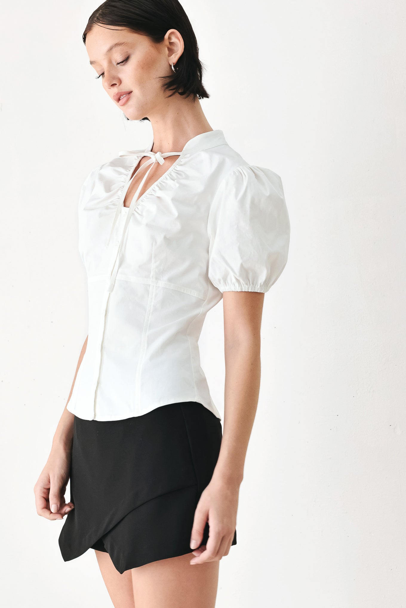 A woman wearing a white short-sleeve blouse with puff sleeves, a ruffled collar, and a keyhole cutout at the neckline | FREEMARKET