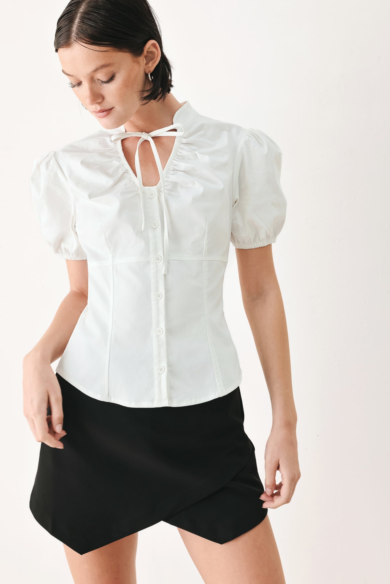A woman wearing a white short-sleeve blouse with puff sleeves, a ruffled collar, and a keyhole cutout at the neckline | FREEMARKET