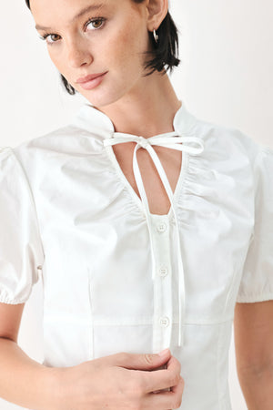 A woman wearing a white short-sleeve blouse with puff sleeves, a ruffled collar, and a keyhole cutout at the neckline | FREEMARKET