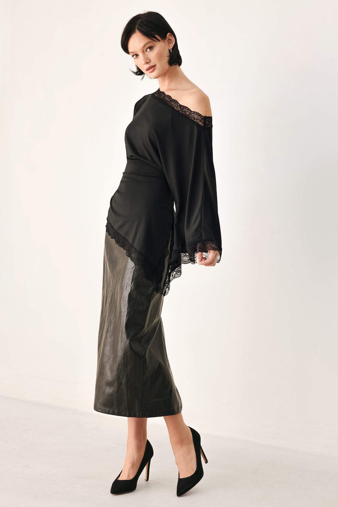 A model wearing a black asymmetrical off-the-shoulder top with black lace trim along the neckline, cuffs, and hem | FREEMARKET