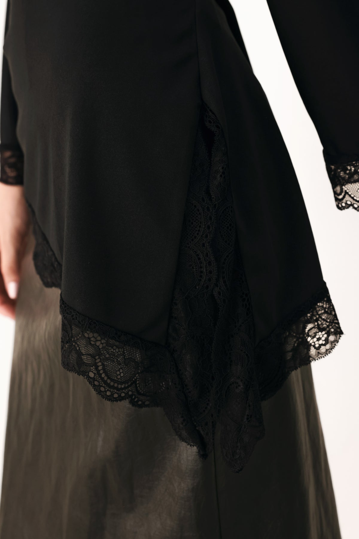 A model wearing a black asymmetrical off-the-shoulder top with black lace trim along the neckline, cuffs, and hem | FREEMARKET