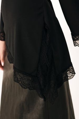 A model wearing a black asymmetrical off-the-shoulder top with black lace trim along the neckline, cuffs, and hem | FREEMARKET