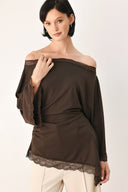 A model wearing a dark brown asymmetrical off-the-shoulder top with brown lace trim along the neckline, cuffs, and hem | FREEMARKET