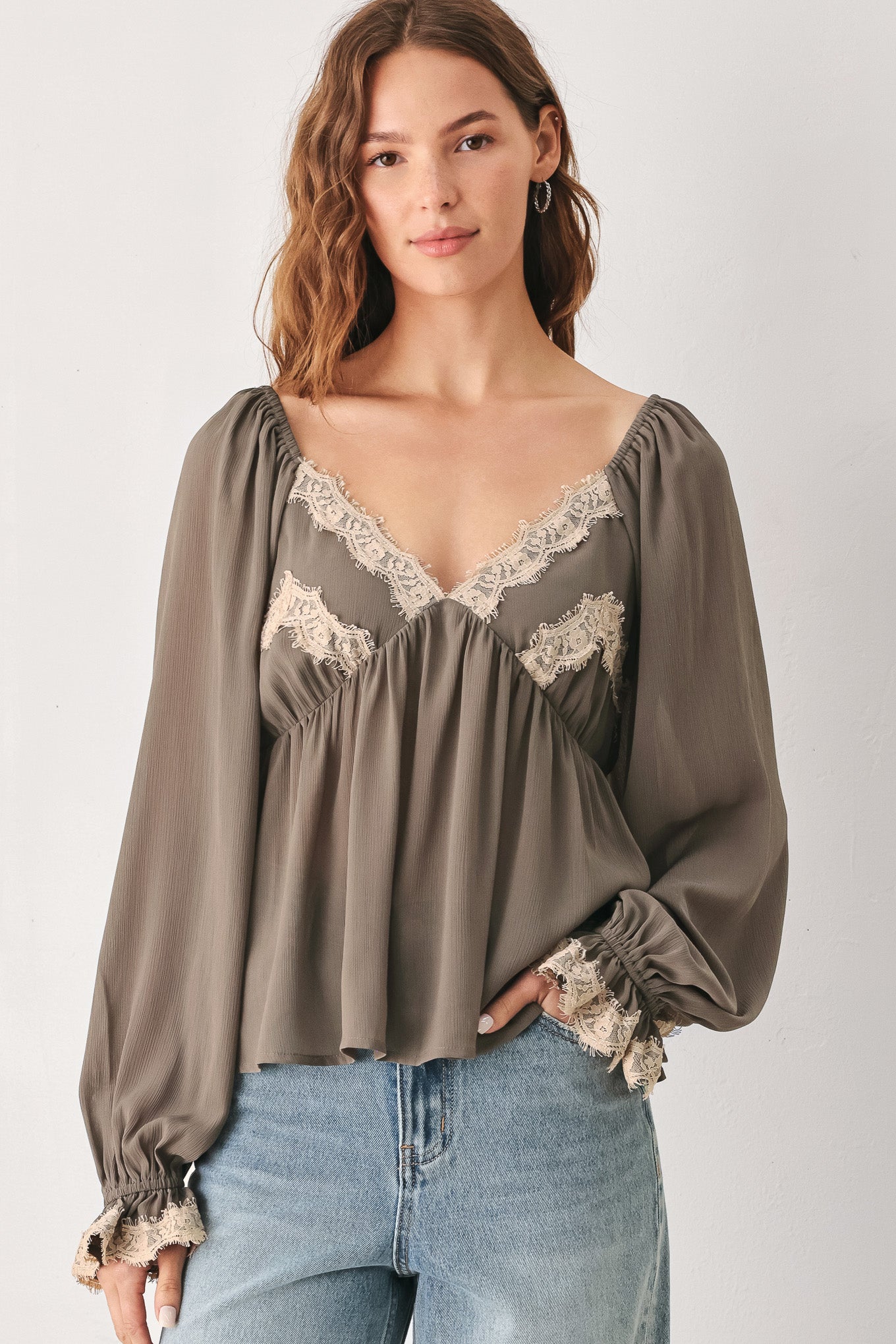 A woman wearing a taupe-brown long-sleeve blouse with beige lace trim on the neckline and cuffs | FREEMARKET