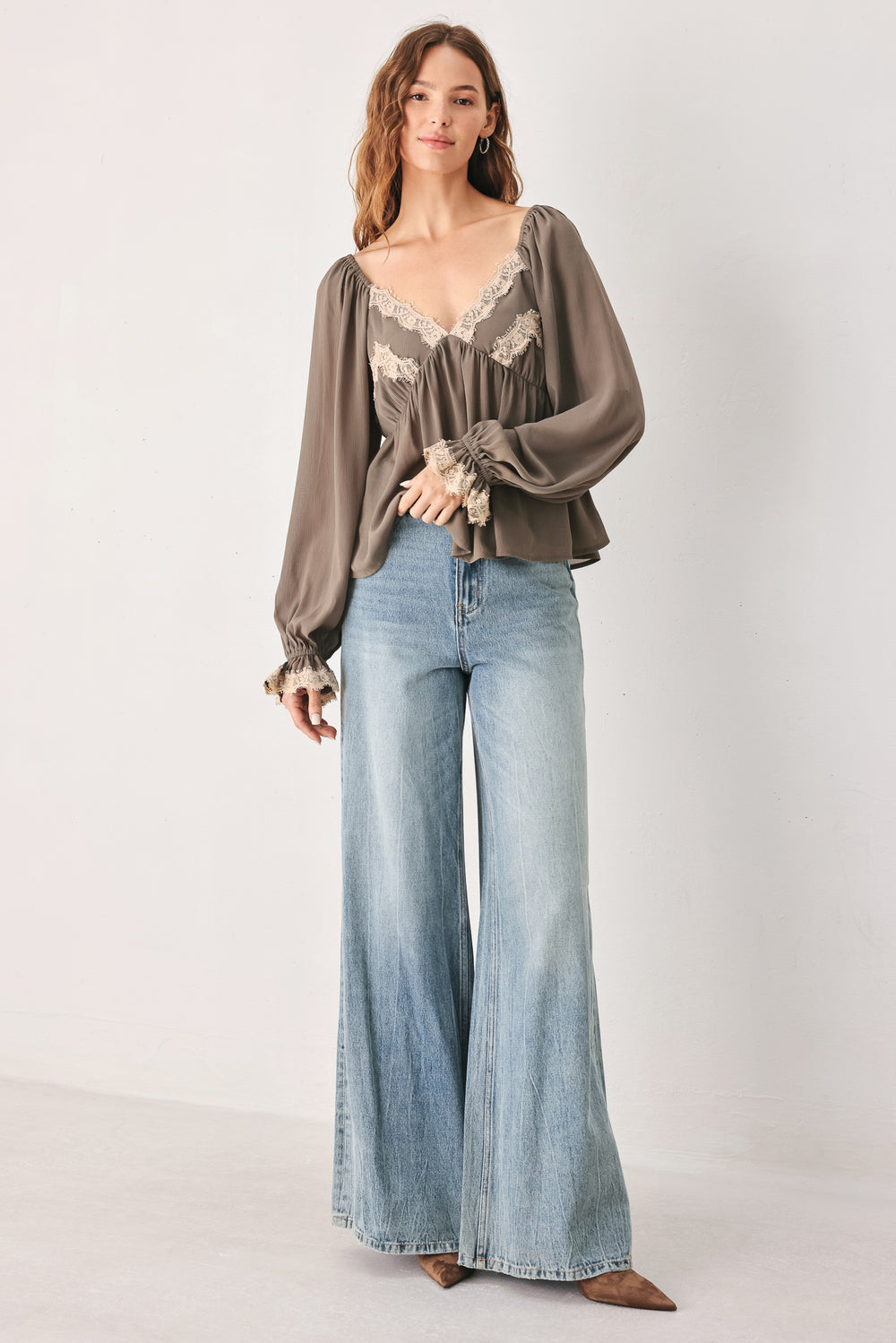 A woman wearing a taupe-brown long-sleeve blouse with beige lace trim on the neckline and cuffs | FREEMARKET
