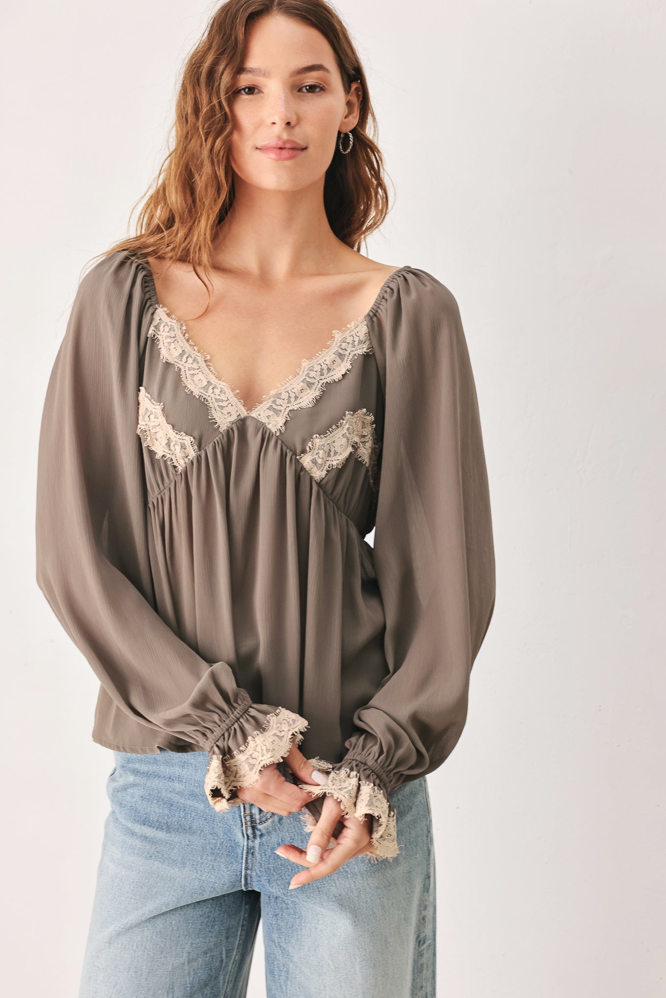 A woman wearing a taupe-brown long-sleeve blouse with beige lace trim on the neckline and cuffs | FREEMARKET