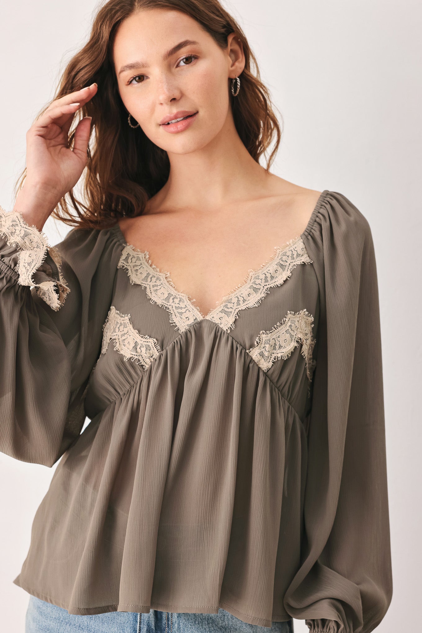 A woman wearing a taupe-brown long-sleeve blouse with beige lace trim on the neckline and cuffs | FREEMARKET