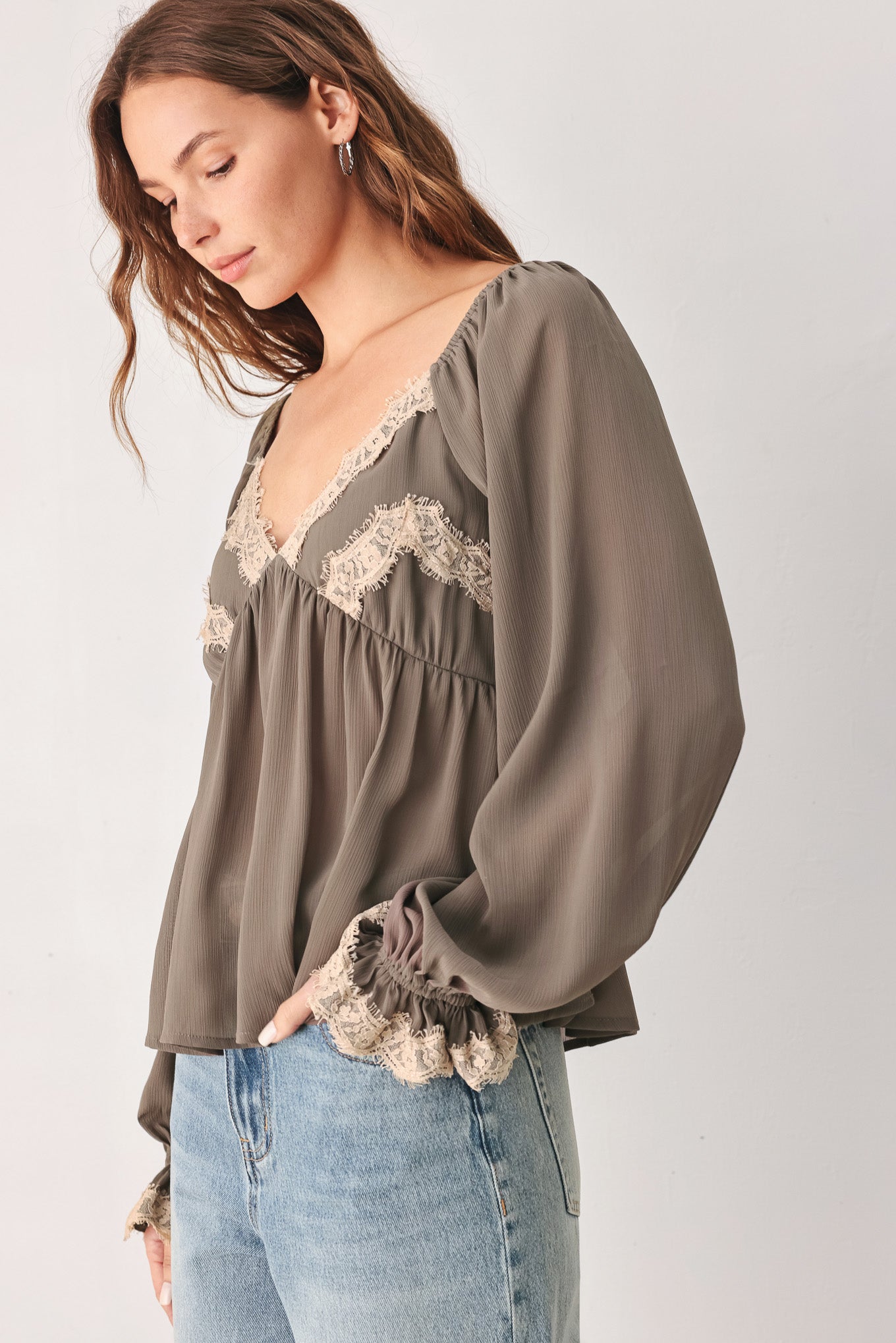 A woman wearing a taupe-brown long-sleeve blouse with beige lace trim on the neckline and cuffs | FREEMARKET