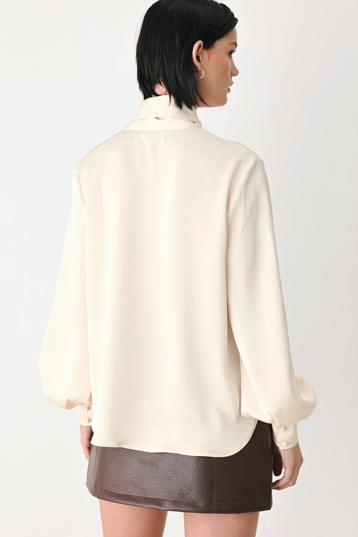 A woman wearing a cream-colored long-sleeve blouse with a tie-neck detail | FREEMARKET