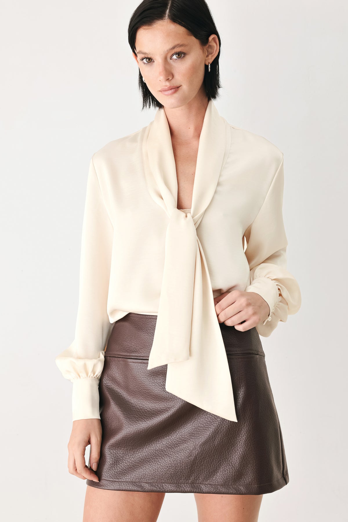 A woman wearing a cream-colored long-sleeve blouse with a tie-neck detail | FREEMARKET