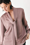 A woman wearing a dusty mauve long-sleeve silk blouse with a shawl collar and front tie | FREEMARKET