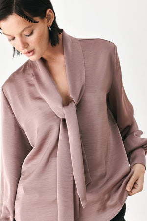 A woman wearing a dusty mauve long-sleeve silk blouse with a shawl collar and front tie | FREEMARKET