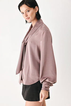 A woman wearing a dusty mauve long-sleeve silk blouse with a shawl collar and front tie | FREEMARKET