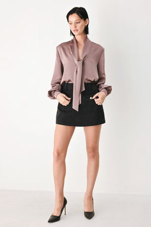 A woman wearing a dusty mauve long-sleeve silk blouse with a shawl collar and front tie | FREEMARKET