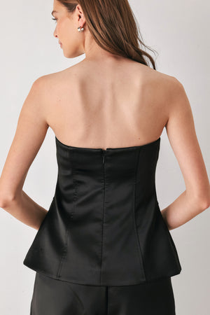 Woman wearing a strapless satin-like top with buttons along the front and two faux pockets | FREEMARKET