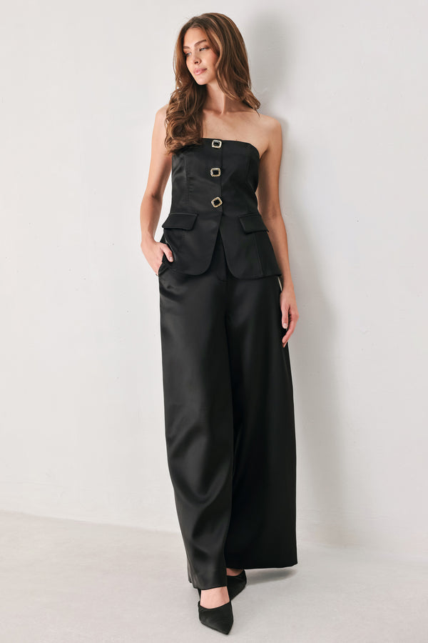 Woman wearing a strapless satin-like top with buttons along the front and two faux pockets | FREEMARKET