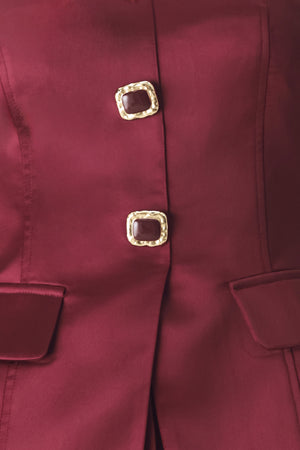 Woman wearing a burgundy strapless satin-like top with buttons along the front and two faux pockets | FREEMARKET