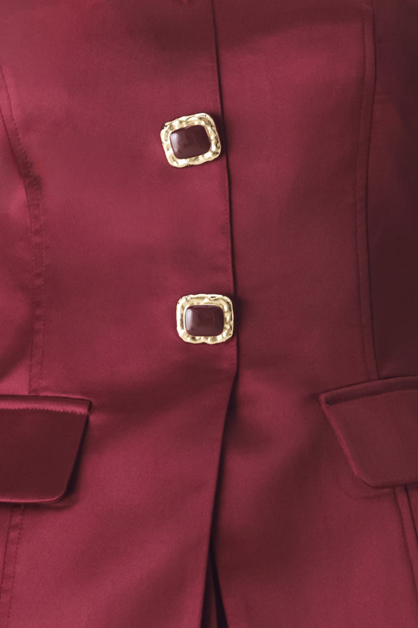 Woman wearing a burgundy strapless satin-like top with buttons along the front and two faux pockets | FREEMARKET